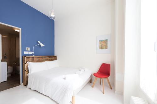 ミラノにあるHeart Milan Apartments Duomo SanBarnabaのベッドルーム(白いベッド1台、赤い椅子付)