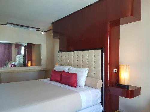 a bedroom with a large bed with two red pillows at Cebu Dulcinea Hotel and Suites-MACTAN AIRPORT HOTEL in Mactan