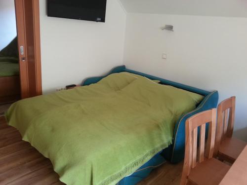 a bed in a room with a green blanket on it at Apartments BBI in Luče