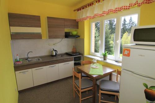 a small kitchen with a table and a refrigerator at Chata Javorina in Javorník