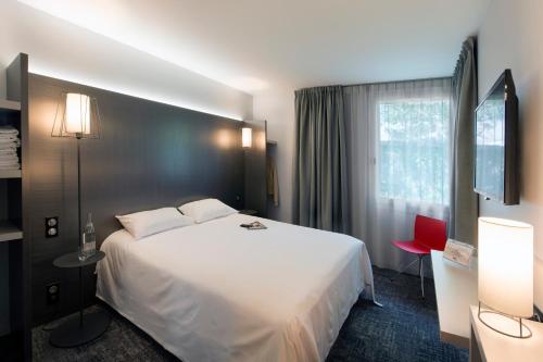 a hotel room with a white bed and a window at L'hôtel by JOA de Saint-Paul-Lès-Dax in Saint-Paul-lès-Dax