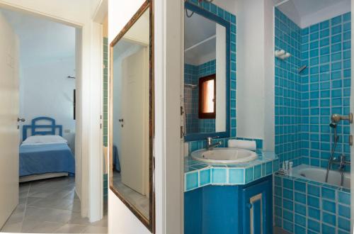niebieska łazienka z umywalką i lustrem w obiekcie Residence I Cormorani Alti w mieście Baja Sardinia