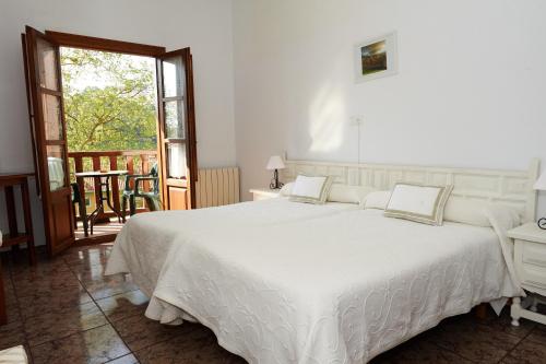 a bedroom with a large white bed and a balcony at Hotel Solatorre in Comillas
