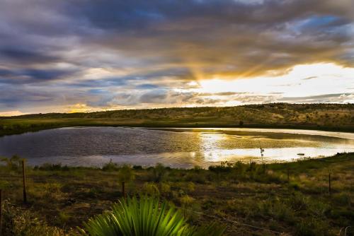a sunset over a pond with a rainbow in the sky at Casa Rural Cruces de Caminos in Plasencia