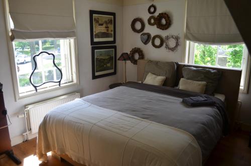 een slaapkamer met een groot bed en 2 ramen bij Bij Janneke in Sleeuwijk