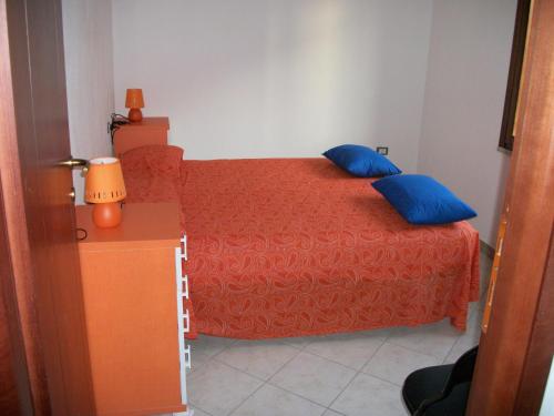 a bedroom with a red bed with blue pillows at Casa Solaria Villetta singola panoramicissima in Costa Rei