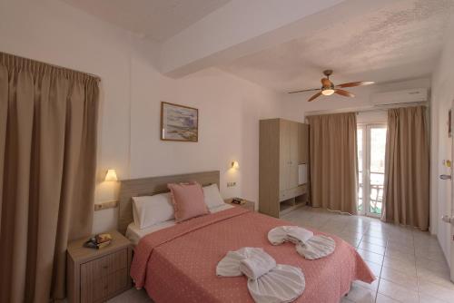 a bedroom with a bed and a ceiling fan at Nikos Hotel in Matala