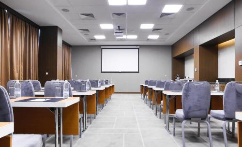 a conference room with tables and chairs and a screen at Radisson Blu Hotel, Abidjan Airport in Abidjan
