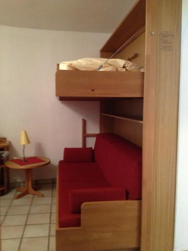 a living room with a red couch and a bunk bed at Appartements Kröll, Joker Card in summer included! in Saalbach Hinterglemm