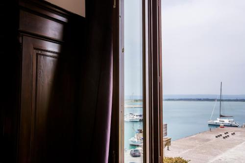 a window with a view of the water and boats at Palazzo Giunta - Porta Marina Ortigia in Siracusa