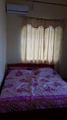a bedroom with a bed with a purple blanket and a window at Amir's Apartment in Nieuw Nickerie