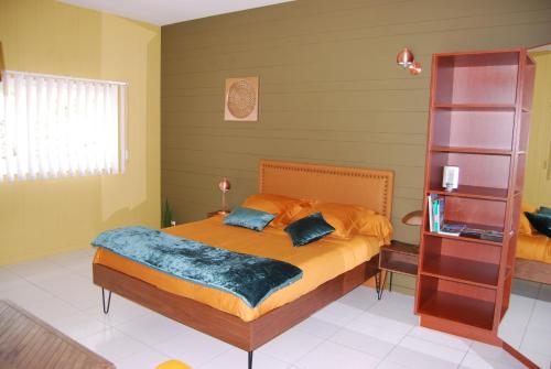 a bedroom with a bed with orange sheets and blue pillows at Kerzara - Le Gîte in Sarzeau