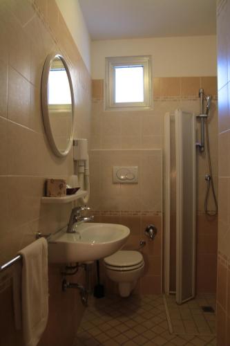 a bathroom with a sink and a toilet and a mirror at Hotel Senyor in Rimini