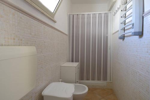 ヴィッラッジョ・モセにあるLa Casuzza Dell'Ulivoの白いトイレとレンガの壁が備わるバスルーム