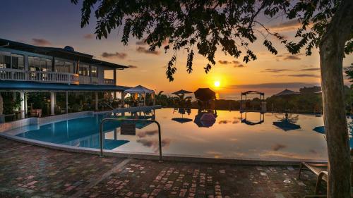 a large swimming pool with a sunset in the background at Cristal Ballena Boutique Hotel & Spa in Uvita