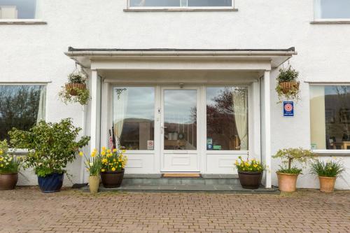 a white entrance to a building with potted plants at Hermiston Guest House in Keswick
