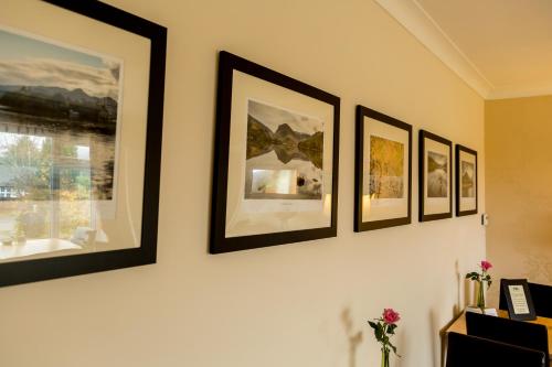 a row of framed pictures on a wall at Hermiston Guest House in Keswick