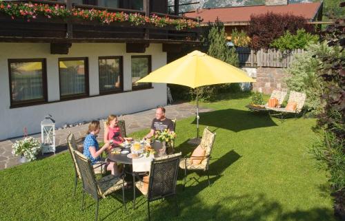 a man and two children sitting at a table under an umbrella at Appartement Rofan in Pertisau