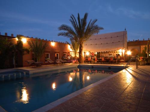 a swimming pool in front of a building at night at Hotel Tomboctou in Tinerhir