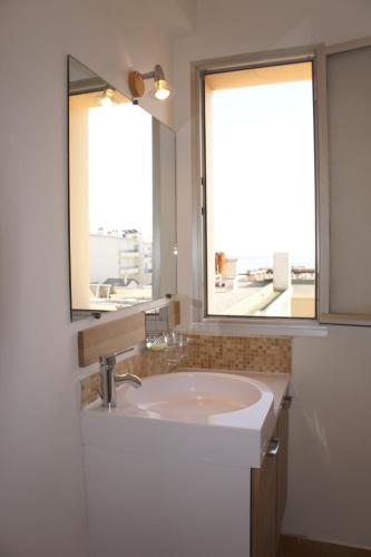 une salle de bain avec un lavabo et deux fenêtres dans l'établissement Le Montana, à Juan-les-Pins