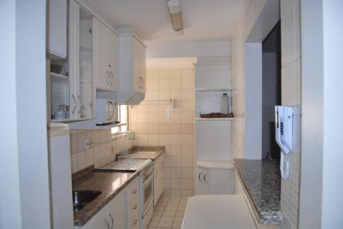 eine Küche mit weißen Schränken und einem weißen Kühlschrank in der Unterkunft Prive das Thermas I - 3 Quartos - Achei Ferias in Caldas Novas