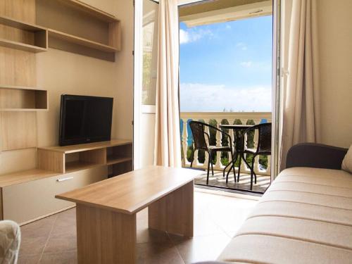 a living room with a couch and a television and a balcony at Hortus Apartments in Sveti Stefan