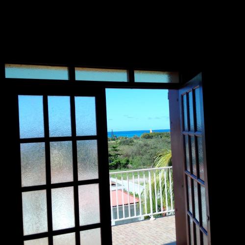 an open door to a balcony with a view of the ocean at Villa Pistaches in Grand-Bourg