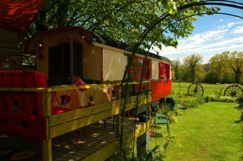 a train parked under a tree in a field at La Roulotte De Lola - Chambre d'hôtes in La Celle