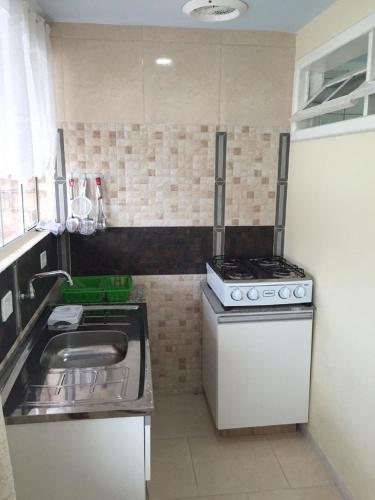 a small kitchen with a stove and a sink at Residencial Samuel in Bombinhas