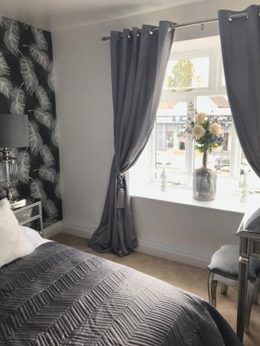 a bedroom with a bed and a window with curtains at Luxury 2 bed Apartment in Witney