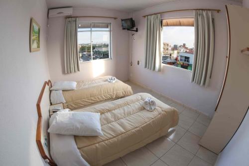 a room with two beds and a couch in it at Hotel Tubarao in Tubarão