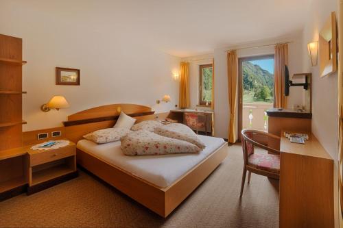 um quarto com uma cama, uma secretária e uma janela em Hotel Mair em Campo Tures