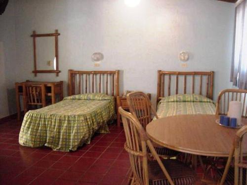 a room with two beds and a table and chairs at Hotel Caribe in Santa Cruz de Barahona