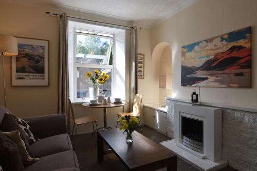 sala de estar con chimenea y mesa en Mansfield Apartment en Hawick