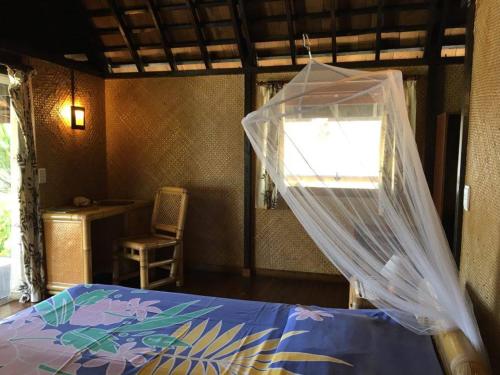 a bedroom with a bed with a net on it at Pension Motu Iti in Pihaena