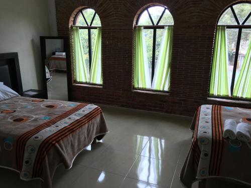 a bedroom with two beds and three windows at Hotel Coatlicue in San Juan Teotihuacán