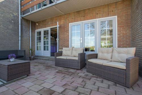 a patio with two wicker chairs and a table at Hotel Eperland in Epen