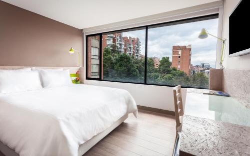 a bedroom with a white bed and a large window at Mika Suites in Bogotá