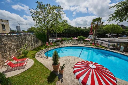 a swimming pool with a red and white umbrella and chairs at Austin Motel in Austin