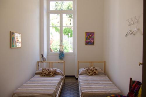 two beds in a room with a window at Oneglia Coast Apt in Imperia