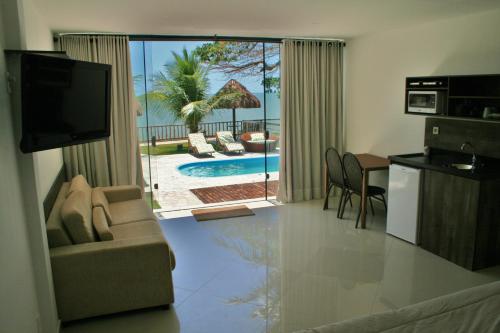 a living room with a couch and a television and a kitchen at Villa Imperador in João Pessoa