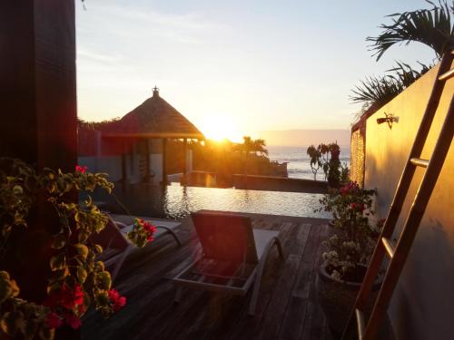 a sunset over a pool with a chair and flowers at Asmara Villa in Nusa Lembongan