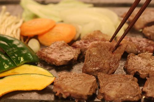 a pile of meat and vegetables on a tray with chopsticks at Syukubo Aso in Aso