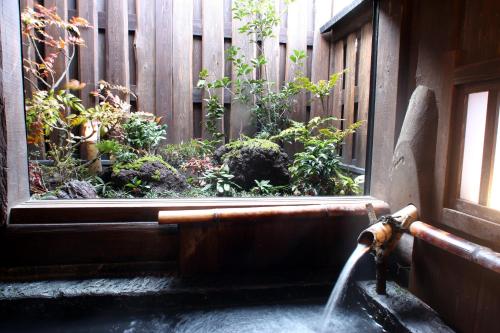 a water fountain in a garden next to a fence at Syukubo Aso in Aso