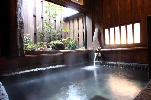 a hot spring in a wooden house with a fountain at Syukubo Aso in Aso