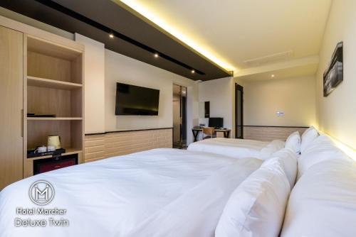 a bedroom with two beds and a flat screen tv at Hotel Marcher in Busan
