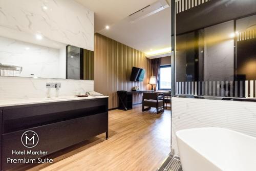 a hotel master bathroom with a tub and a sink at Hotel Marcher in Busan