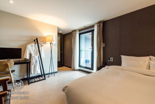 a hotel room with a bed and a desk and a window at Hotel Marcher in Busan