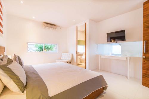 a white bedroom with a bed and a desk at Villa Kamag Seminyak in Seminyak