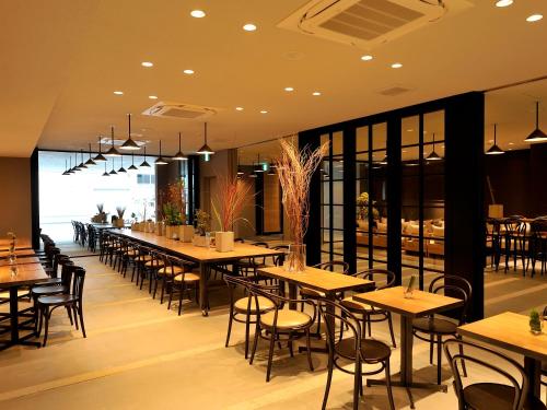 فندق وغرف أوساكا هوماتشي في أوساكا: مطعم بطاولات وكراسي ونافذة كبيرة